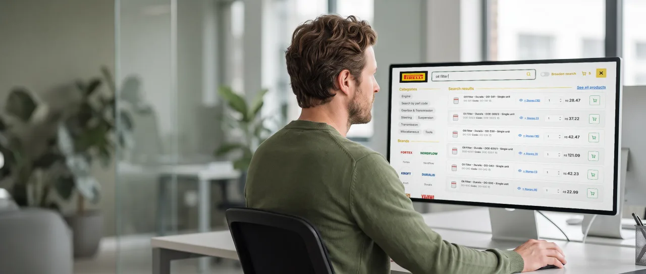 CIO in a cardigan, seated at a desk, looking at a large monitor; the screen shows Pirelli Conecta search with categories, brands and products.
